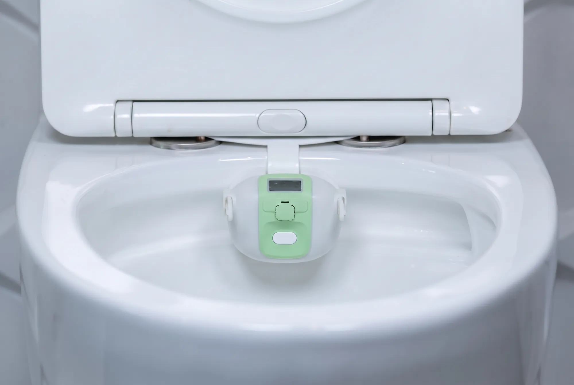 CareTech Human sensor unit clipped to the rim of a toilet bowl in a bright bathroom